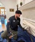 A Premium Chimneys technician cleaning a covered fireplace