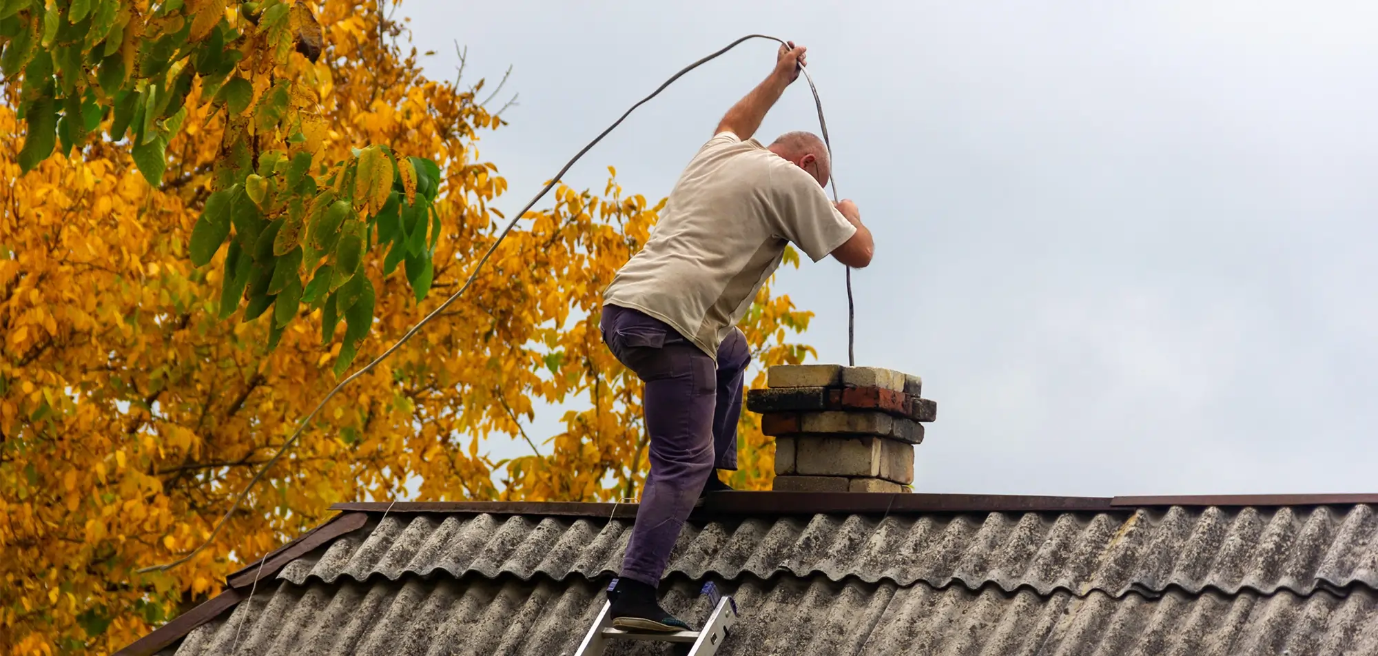 Chimney sweep cleaning a residential flue with professional brushes